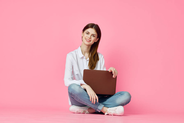 woman with laptop sitting on floor technology internet shopping pink background - Фото, изображение