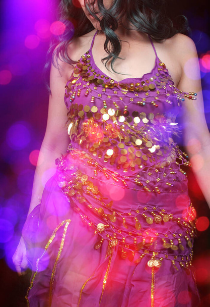 Buikdanseres in paars danskostuum close-up met kleurrijke bokeh - Foto, afbeelding