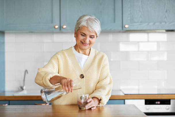 happy woman with jug of water on kitchen at home - Fotoğraf, Görsel