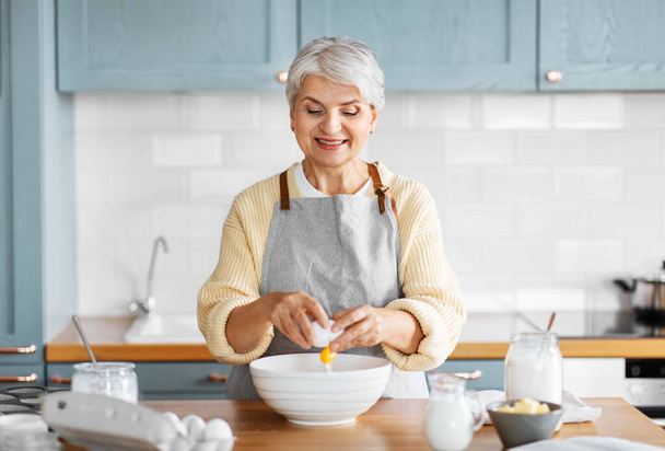 happy woman cooking food on kitchen at home - Φωτογραφία, εικόνα