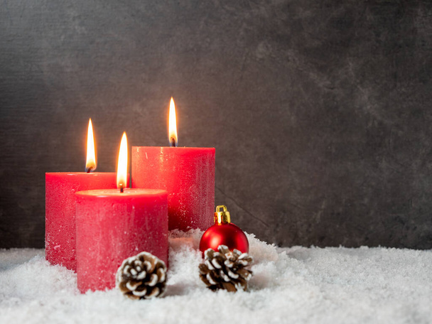 Червона різдвяна свічка та різдвяні прикраси на сірому фоні
. - Фото, зображення