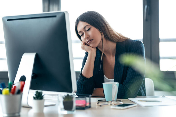 Aufnahme einer eleganten Geschäftsfrau, die schläft, während sie mit dem Computer im Büro arbeitet. - Foto, Bild