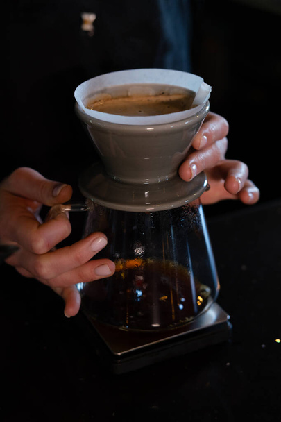 barista nalít horkou vodu na hrubě hnědé bubliny kávy přes kapací filtr, domácí vaření. příprava kávy pomocí chemex nalít na kávovar a kapací konvice. Alternativní způsoby vaření kávy. - Fotografie, Obrázek