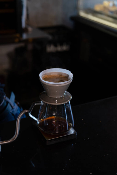 Kahveci kahve köpüğünün üzerine sıcak su döker kahve damlatarak süzgeçten geçer, ev yapımı. Kahve makinesi ve su ısıtıcısının üzerine kimya dökümü kullanarak kahve hazırlıyorum. Kahve yapmak için alternatif yollar.. - Fotoğraf, Görsel