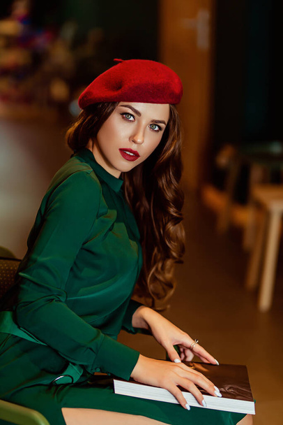 young european woman in a bookstore, a brightly dressed lady in a beret with a book - Foto, immagini