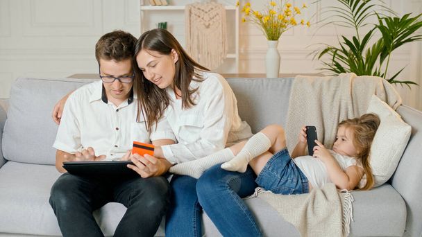 Родители делают покупки в Интернете, в то время как их дочь играет в онлайн-игры Телефон - Фото, изображение
