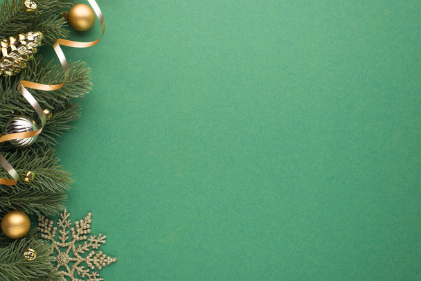 Foto vista dall'alto di oro e argento albero di Natale palle giocattolo cono piccole campane fiocco di neve e serpentino su ramoscelli di pino su sfondo verde isolato con spazio vuoto - Foto, immagini