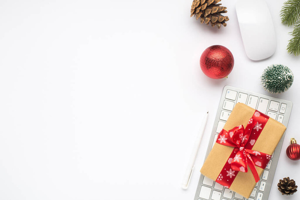 Top view kuva lahjapakkauksessa punainen keula näppäimistöllä tietokoneen hiiri kynä punainen joulukuusi pallot kuusen lelu oksa mänty kartio eristetty valkoinen tausta tyhjä tila - Valokuva, kuva