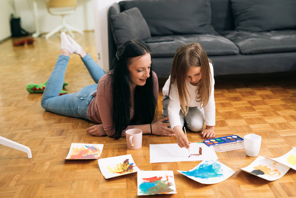 mother and her daughter painting with water colors at home - Foto, imagen