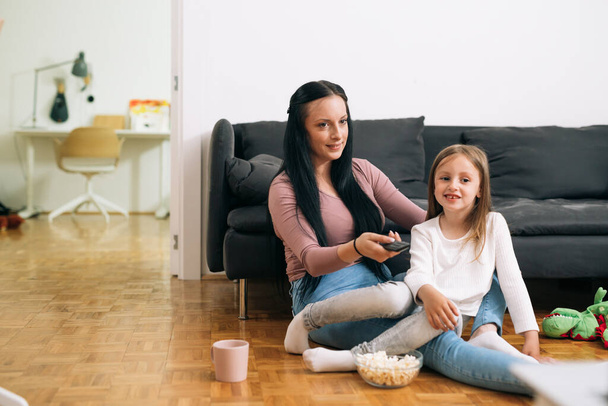 mother and daughter watching tv at home - Fotoğraf, Görsel
