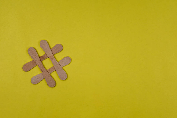 Hash tag symbol made from wooden sticks on blue paper background with copy space for text - 写真・画像