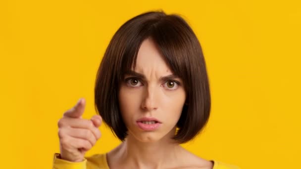 Femme en colère vous blâmant pointant du doigt à la caméra, fond jaune - Séquence, vidéo