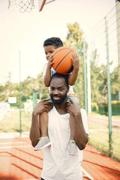 Young black father holding on shoulders his little multiracional son - Foto, Bild