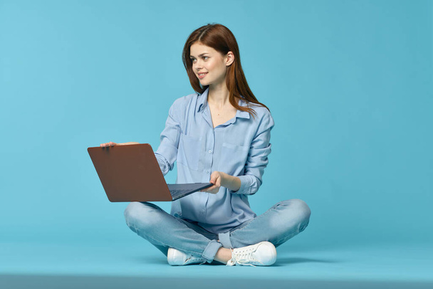 woman with laptop sitting on the floor learning student technology blue background - Fotografie, Obrázek