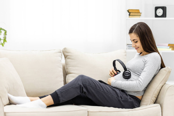 Photo of young pregnant woman with headphones. - Foto, Imagem