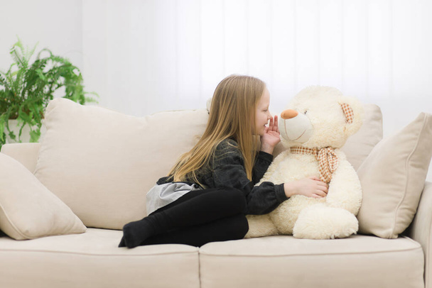 Photo of little girl playing with white teddy bear. - Фото, изображение