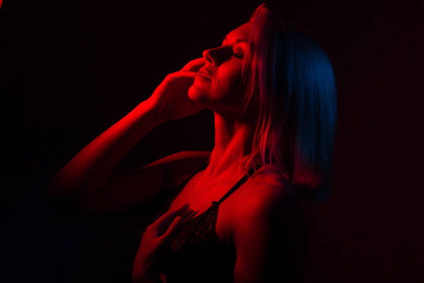 portrait of a blonde girl close-up in a room with red and blue light - Фото, изображение