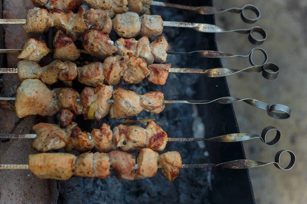 串焼き、ケバブ、または伝統的なシャフリークの揚げ豚肉は、ディナーテーブルの上に設定する準備ができて、たき火を脱いで. - 写真・画像