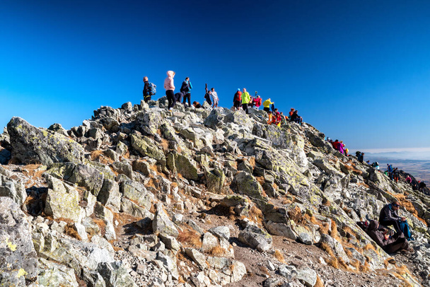 PODBANSKE, ESLOVAQUIA - 31 DE OCTUBRE DE 2021: Muchos excursionistas en la cima del Krivan pico en la montaña de los Altos Tatras - Foto, imagen