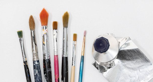 Künstler Pinsel und Quetsche Ölfarbe Tube auf weißem Leinwand-Hintergrund - Foto, Bild