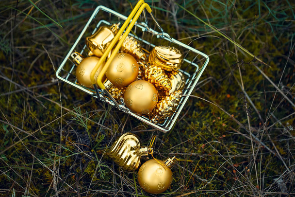 Gouden kerstboom speelgoed in een mandje op een natuurlijke achtergrond. Ballen, kegels, lantaarns, ijspegels, harten. Feestelijke tradities. - Foto, afbeelding