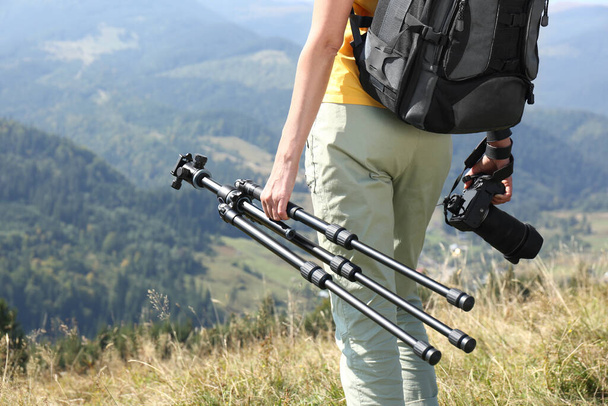 Woman with modern camera and tripod in mountains, closeup - Фото, изображение
