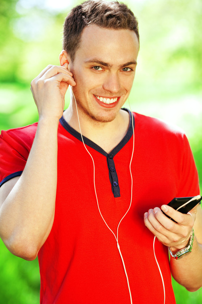Portrait of happy young man in red t-shirt listening to music on - Fotó, kép