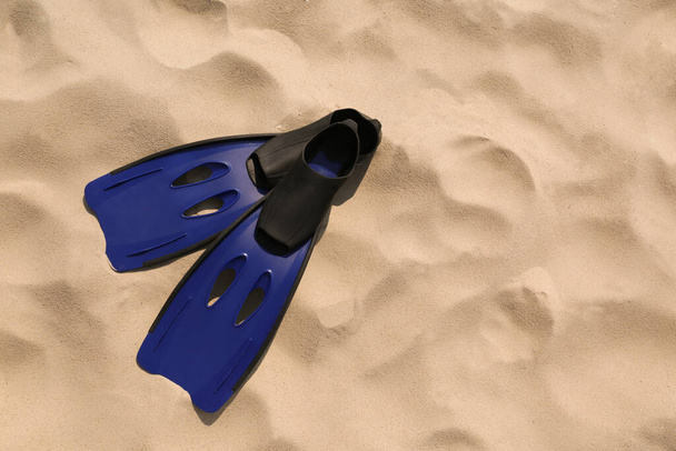 Pair of blue flippers on sand, top view. Space for text - Foto, Imagen