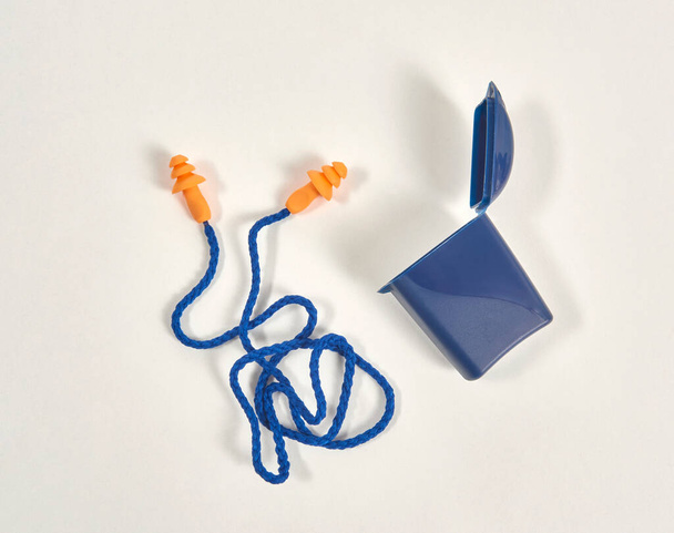 Tappo per le orecchie e scatola isolata sullo sfondo bianco, prodotto blu e arancione. - Foto, immagini