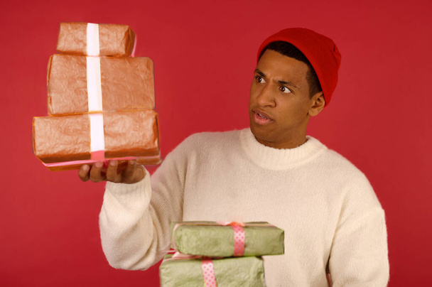 Темнокожий возбужденный молодой парень с подарочными коробками в руках - Фото, изображение