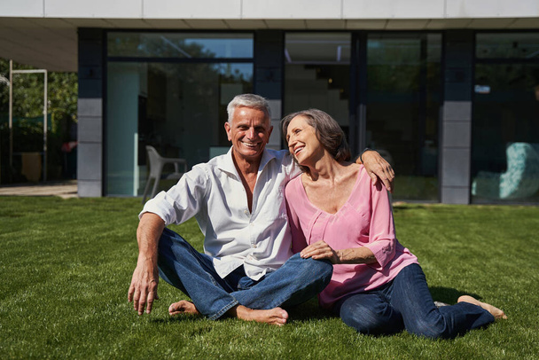 Elderly man and aging lady sitting together before house - Foto, Imagem