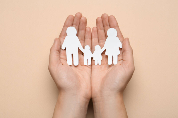 Woman holding paper family cutout on beige background, top view - Foto, Imagem