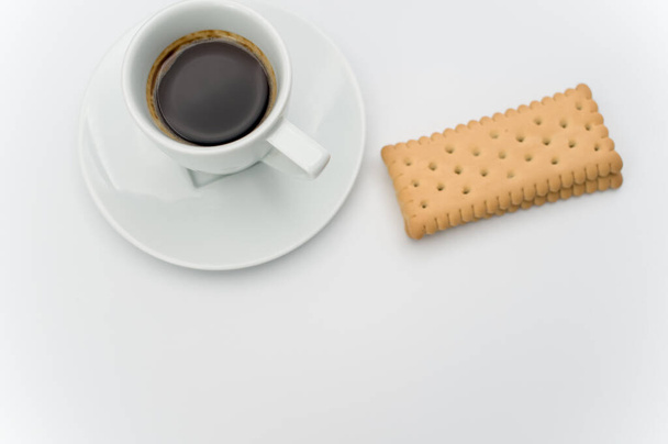 black hot ristretto coffee in a white stoneware cup with plate and biscuits on a white surface with text space - Photo, Image