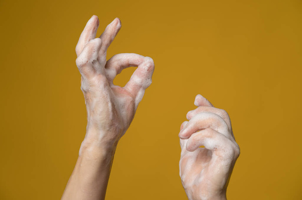 Hands in soapy foam, one of them shows a ok sign with her fingers. Concept for an effective way to prevent the spread of infections.  - Fotoğraf, Görsel