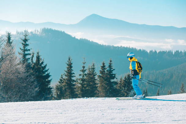 жінка катається на лижах вниз по зимових схилах гори на фоні
 - Фото, зображення