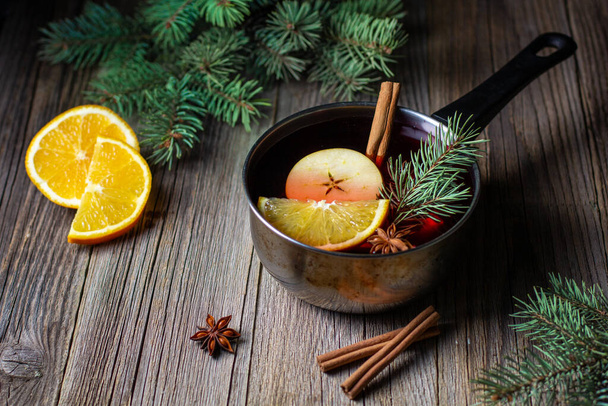tasty mulled wine with mandarin orange apple spices and christmas tree in pot. Autumn hot drink - Photo, Image