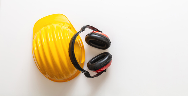 Safety equipment helmet and ear muffs. Head and hearing protection isolated on white background, banner. Personal protective head gear, yellow hard hat and headphones - Photo, Image