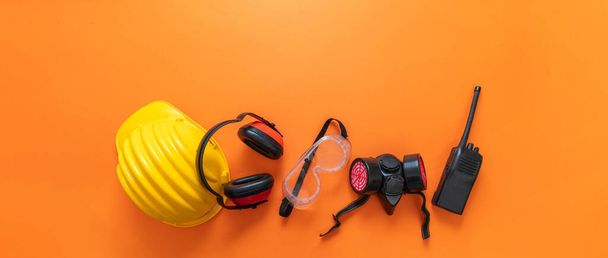 Arbeitsschutzkonzept für Industriebauarbeiter. Arbeitskleidung Schutzausrüstung auf orangefarbenem Hintergrund, persönliche Schutzausrüstung, Draufsicht. - Foto, Bild