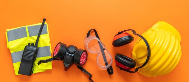 Industrial construction site worker health and safety concept. Work wear protection equipment on orange color background, personal protective gear, top view. - Photo, Image