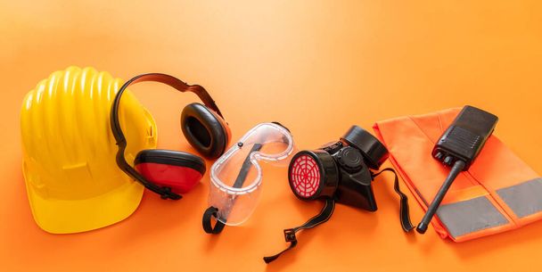 作業は、オレンジ色の背景、個人用保護具に安全保護装置を着用してください。工業建設現場労働者の健康と安全の概念. - 写真・画像