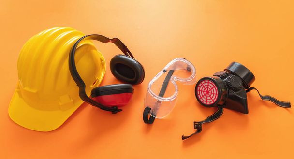 Arbeitskleidung Schutzausrüstung auf orangefarbenem Hintergrund, persönliche Schutzausrüstung. Gesundheits- und Sicherheitskonzept für Industriearbeiter auf der Baustelle. - Foto, Bild