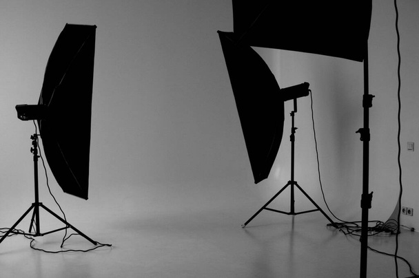 A grayscale shot of a photoshoot studio with three lightboxes on a white screen background. - Φωτογραφία, εικόνα