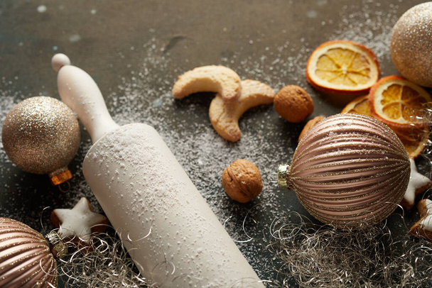 A rolling pin, Christmas baubles, and biscuits on the table - Foto, imagen