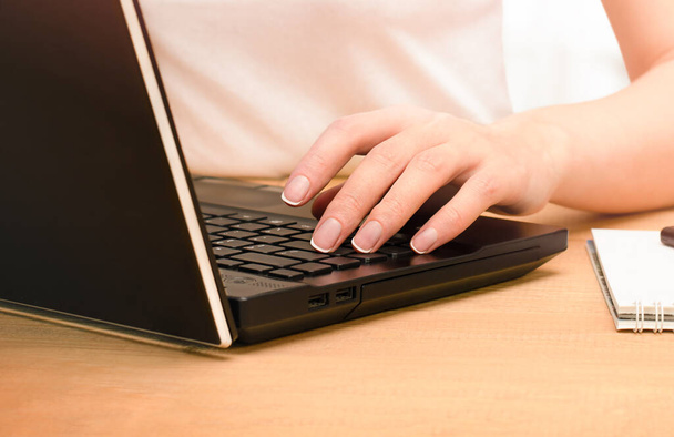 mano femminile digitando testo su un computer portatile seduto a un tavolo, primo piano - Foto, immagini