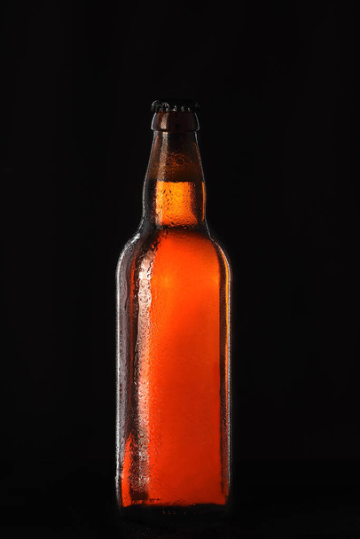 full glass bottle of beer on a black background - Фото, изображение