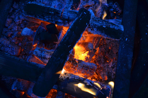 Flaring fire on coals. Close-up view of barbecue charcoal on fire. Red-hot coals in the fire. Background for design. - 写真・画像