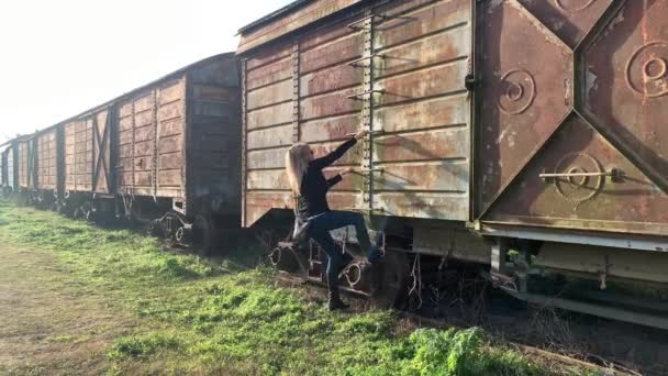 Eine erwachsene Frau klettert auf die Seitenleiter eines verlassenen Güterwagens. Konzept verlassener Orte - Filmmaterial, Video