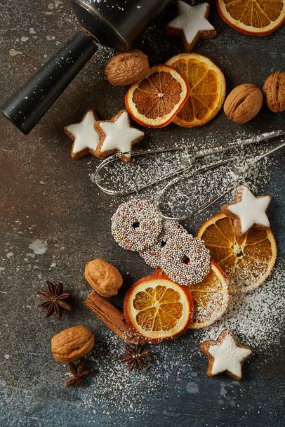 A top view of Christmas cookies, dry oranges, nuts, and baking toolson the table - Foto, Imagem