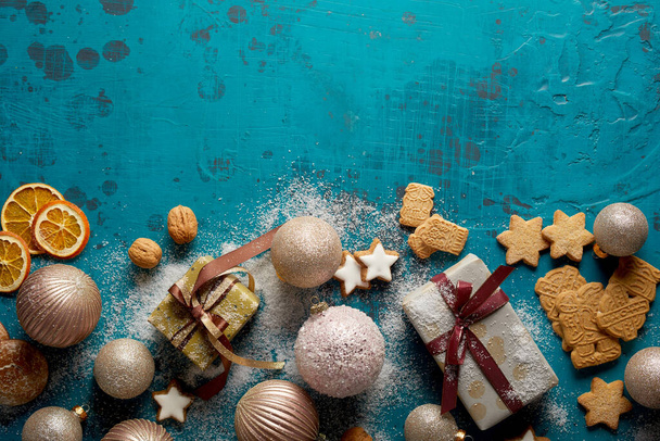 Yummy Christmas cookies, baubles, and gift boxes arranged on the grunge blue surface; background with a copy space - Photo, image
