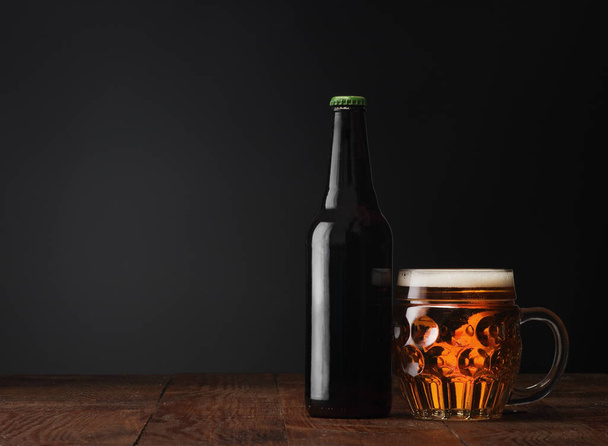 garrafa de cerveja com uma caneca cheia em um fundo preto - Foto, Imagem